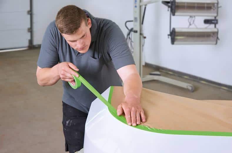 a worker applies tesa 4338 high performance masking tape to a surface in order to mask it off for a spray-painting coat. The tape quick to stick thanks to its high initial tack and bond strength.