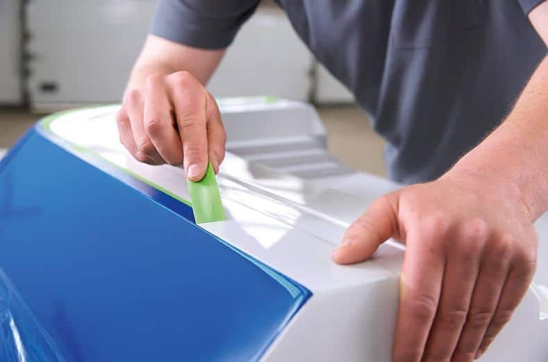 a worker removes tesa 4338 high performance masking tape from a surface after the paint has been through oven-drying cycles. The masking tape’s removal is residue-free and leaves a straight, clean paint edge.